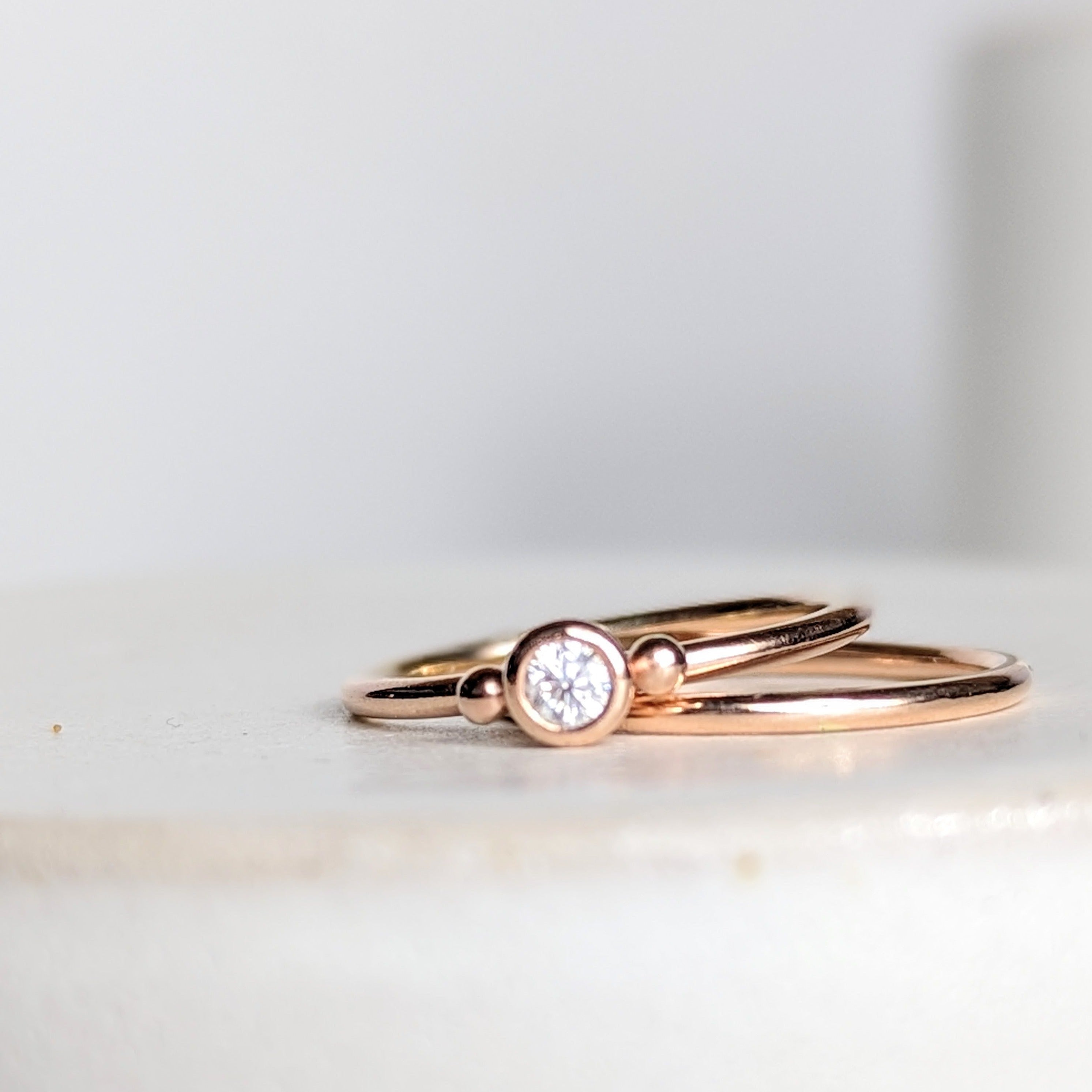 Dainty rose gold stacking rings with sparkly moissanite DEI collection on white background