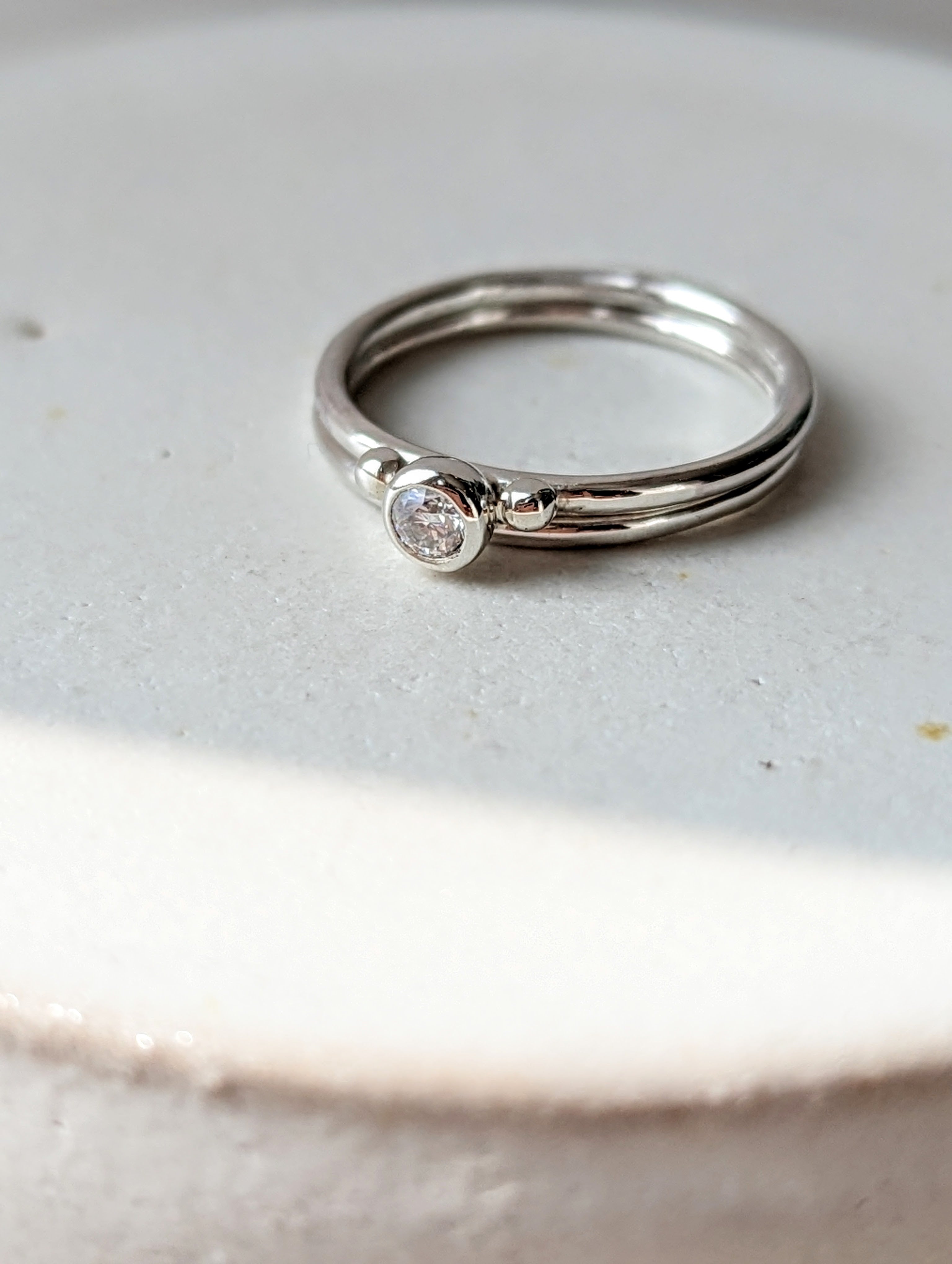 two Silver minimalistic stacking rings with sparkly moissanite and two granules on white background Dei Collection