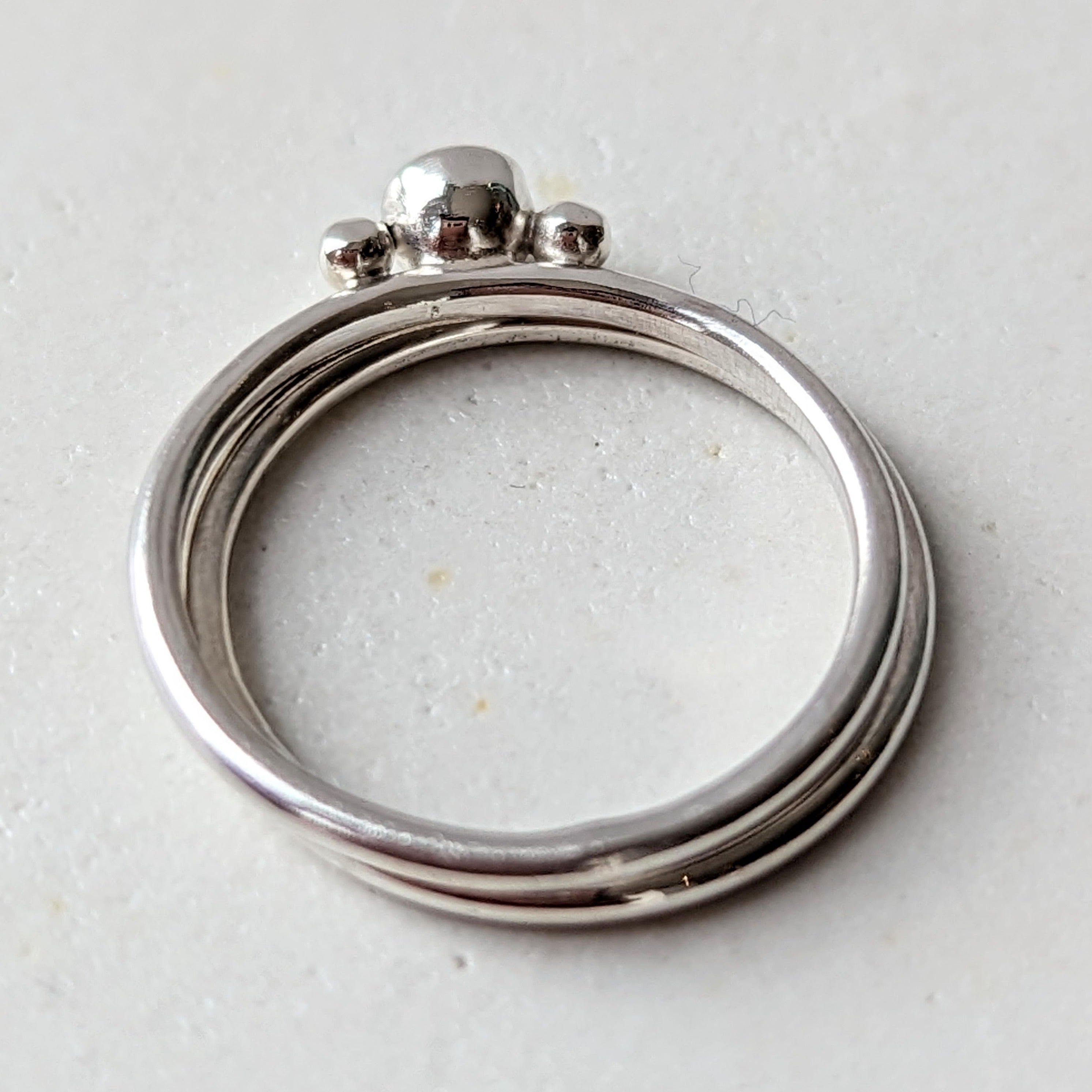 two Silver minimalistic stacking rings with sparkly moissanite and two granules on white background Dei Collection top view