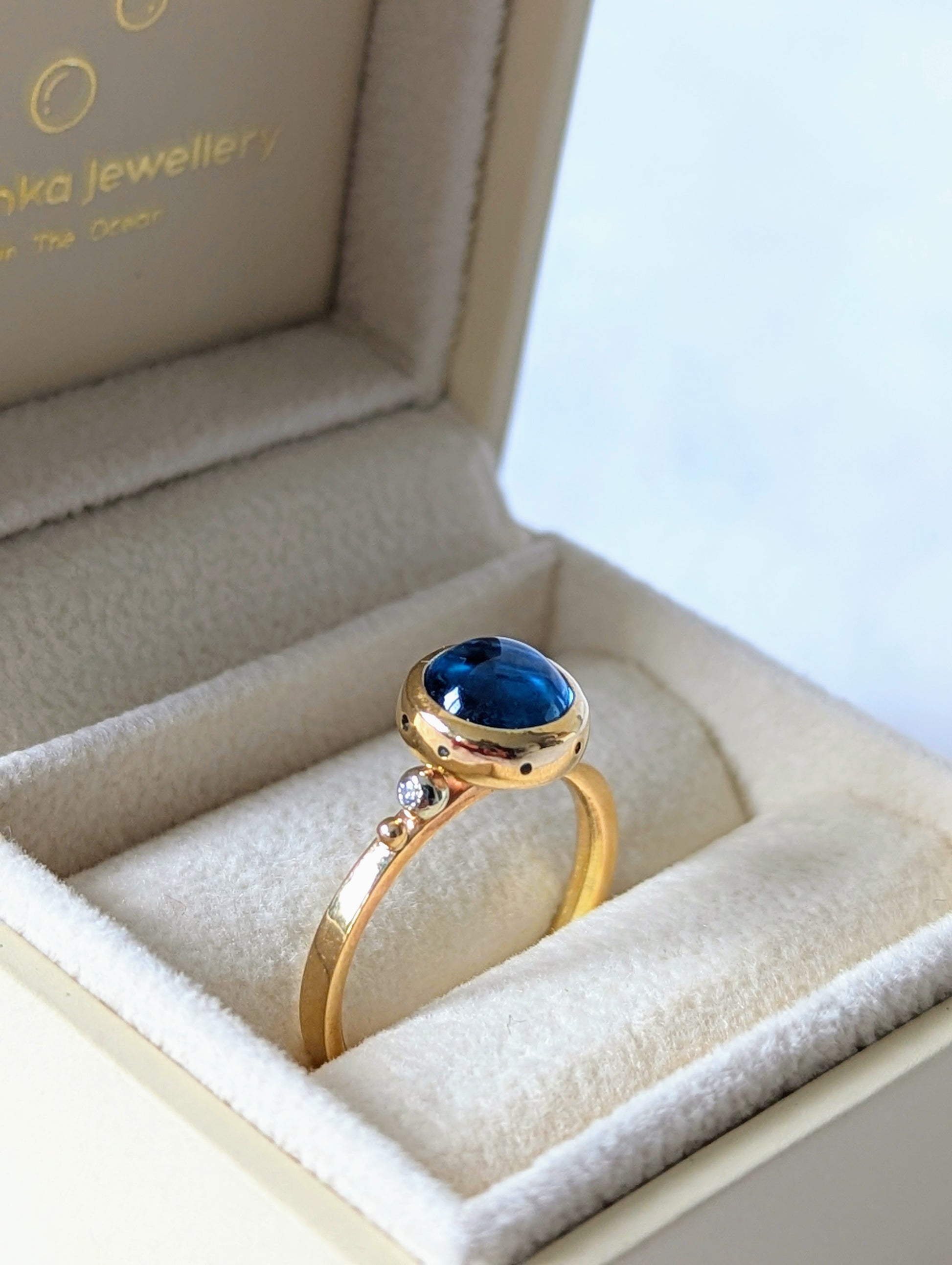 Swiss Blue Topaz Cabochon Gold Ring – Drop of the Ocean Collection in an ivory jewellery box