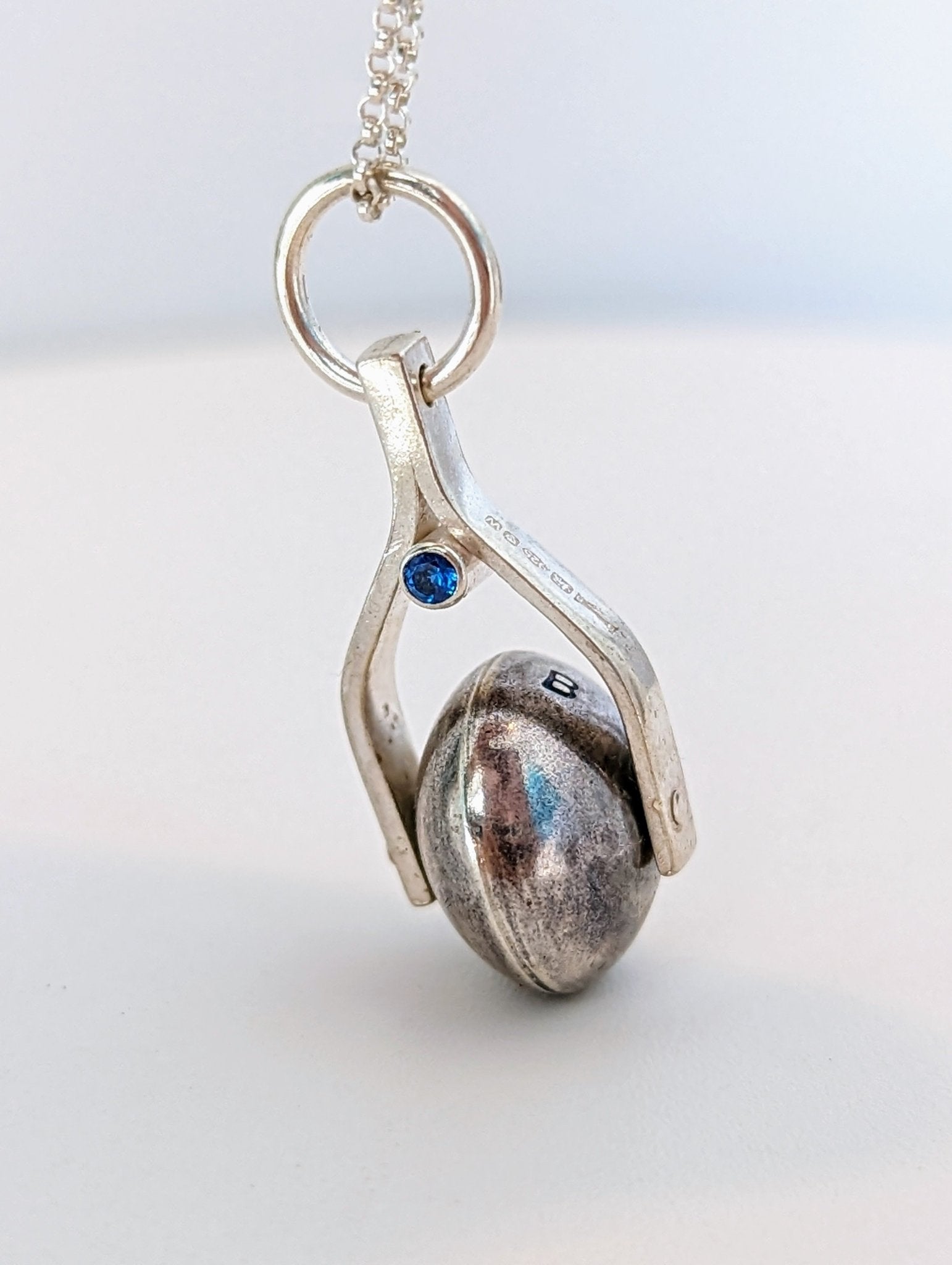 Detailed shot of the spinning moon necklace in sterling silver with a blue gemstone, showcasing its unique design as seen in 'Playing Nicely' by Booblinka Jewellery 