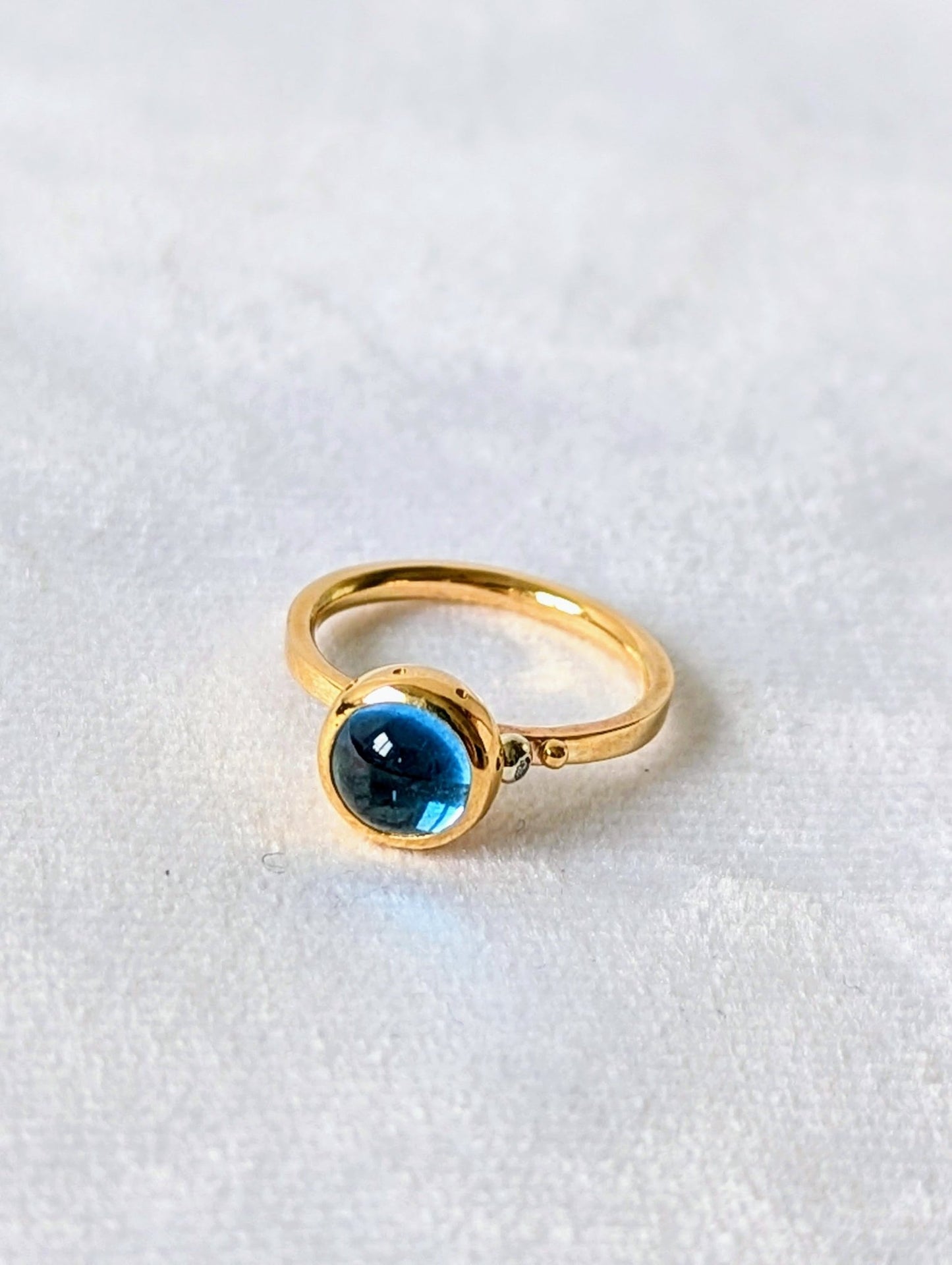 Swiss Blue Topaz Cabochon Gold Ring with diamond from Drop of the Ocean Collection on white velvet made by Booblinka Jewellery