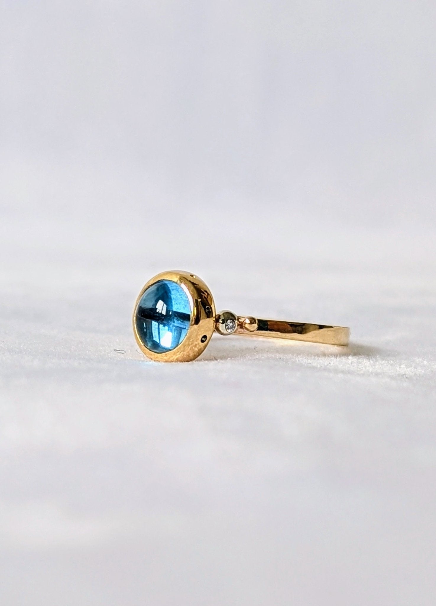 Side view and detail of the diamond on Swiss Blue Topaz Cabochon Gold Ring with diamond from Drop of the Ocean Collection made by Booblinka Jewellery