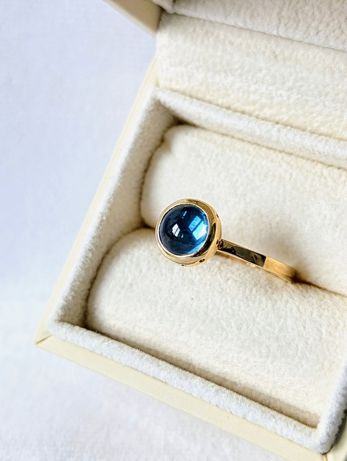 Detail of Swiss Blue Topaz Cabochon Gold Ring with diamond from Drop of the Ocean Collection in ivory jewellery box made by Booblinka Jewellery