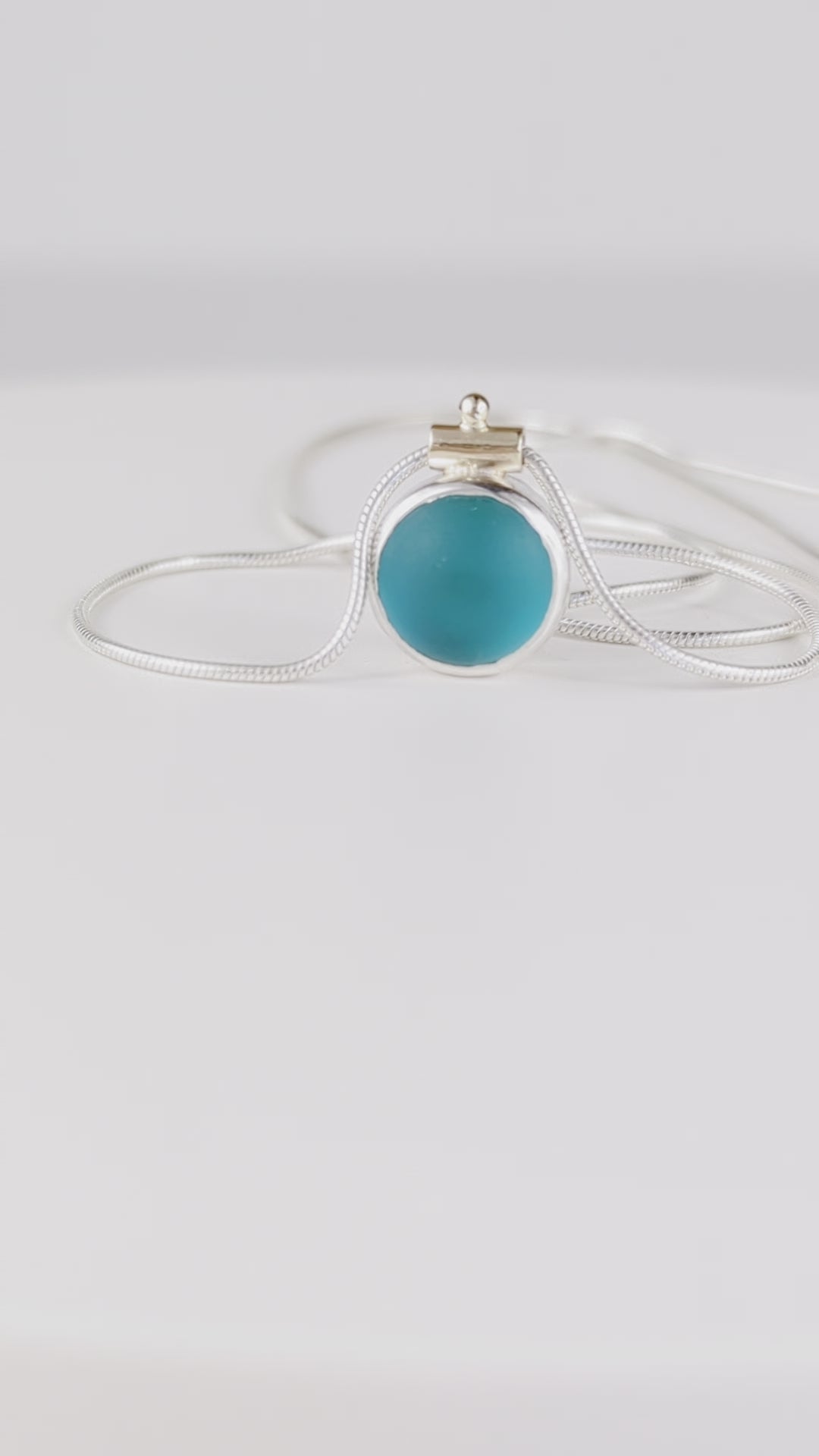 video of spinning deep teal sea glass necklace with gold bail detail and silver snake chain
