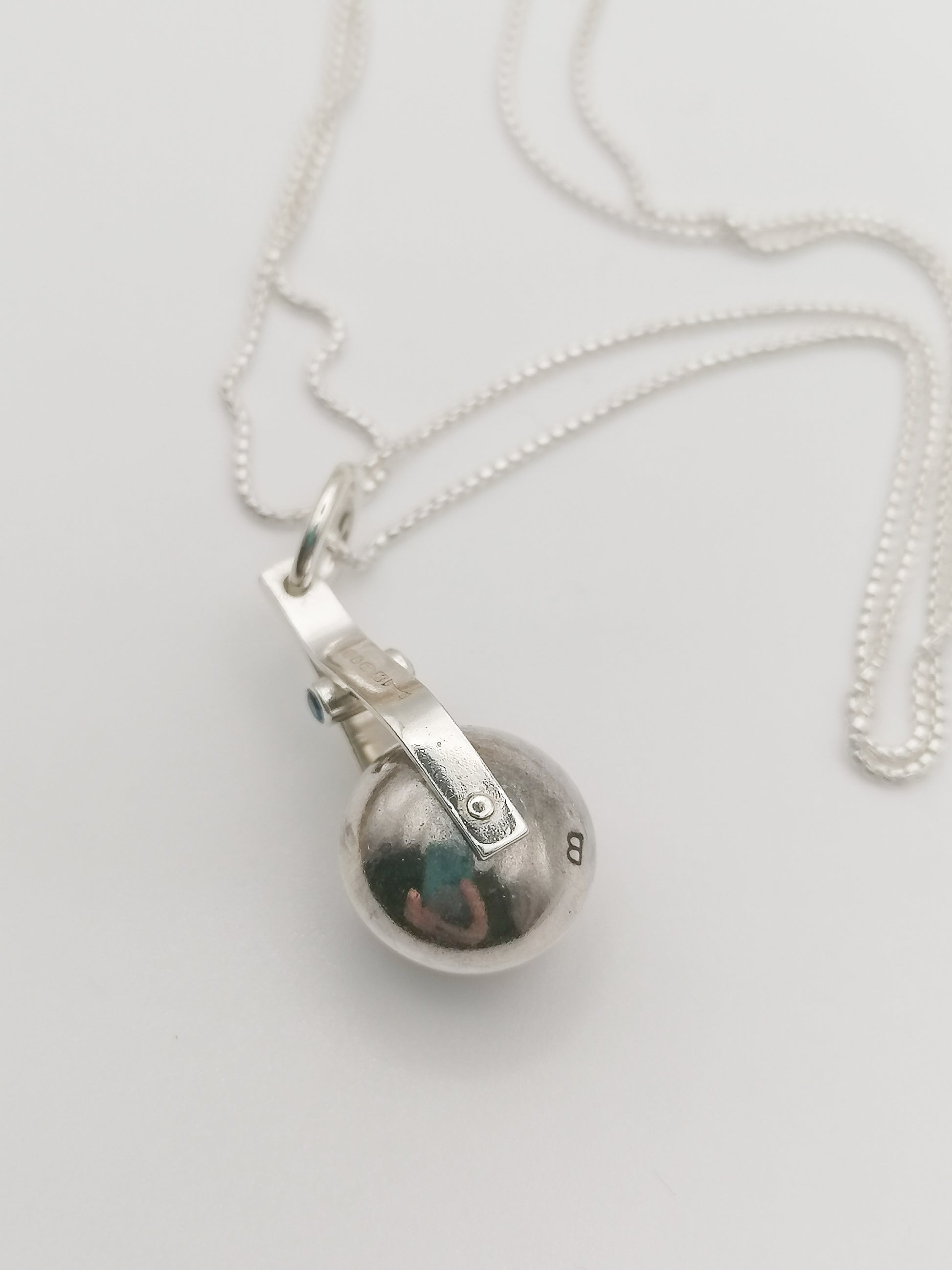 Shot of the spinning moon necklace in sterling silver with a blue gemstone, showcasing its unique design as seen in 'Playing Nicely' by Booblinka Jewellery