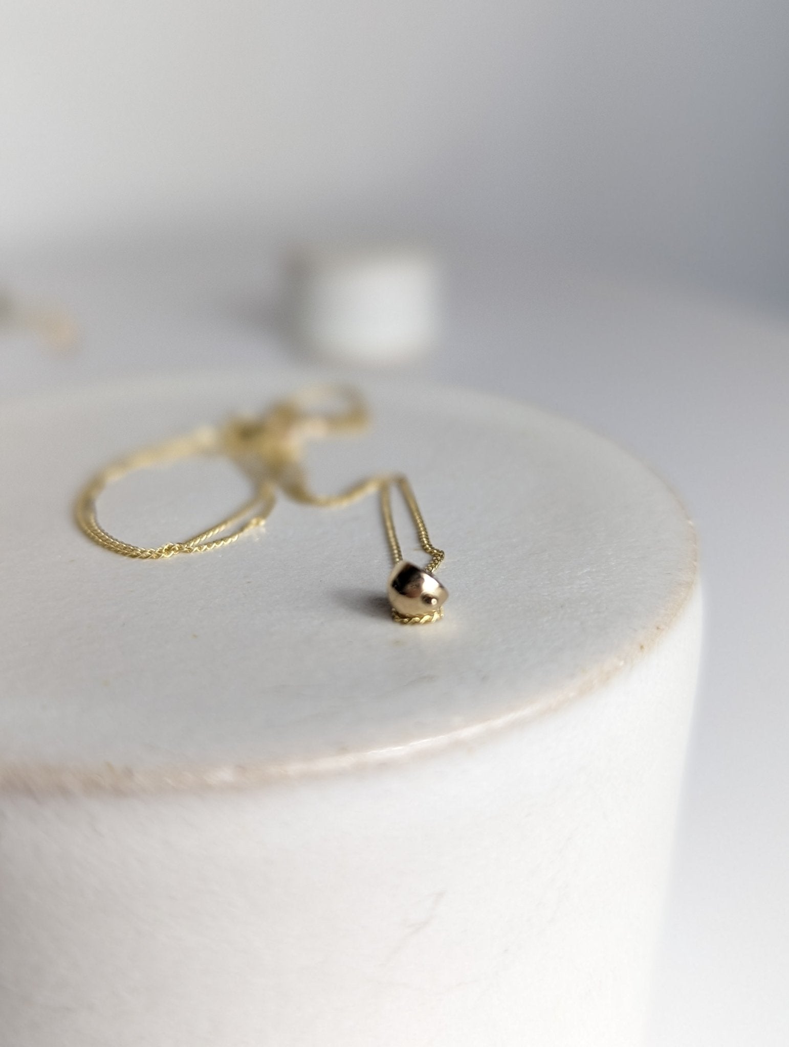 Dainty gold DEI necklace on white ceramic cylinder - Booblinka Jewellery